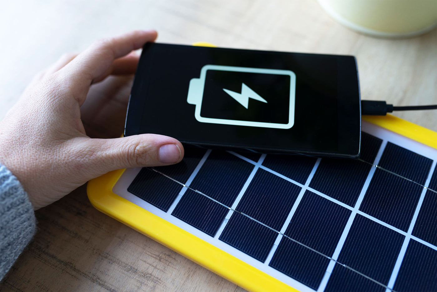 Eine Handy hält ein Handy, das von dem Strom aus einem Solarpanel aufgeladen wird.